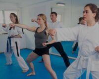 A diverse group of adults practicing punches in a martial arts class