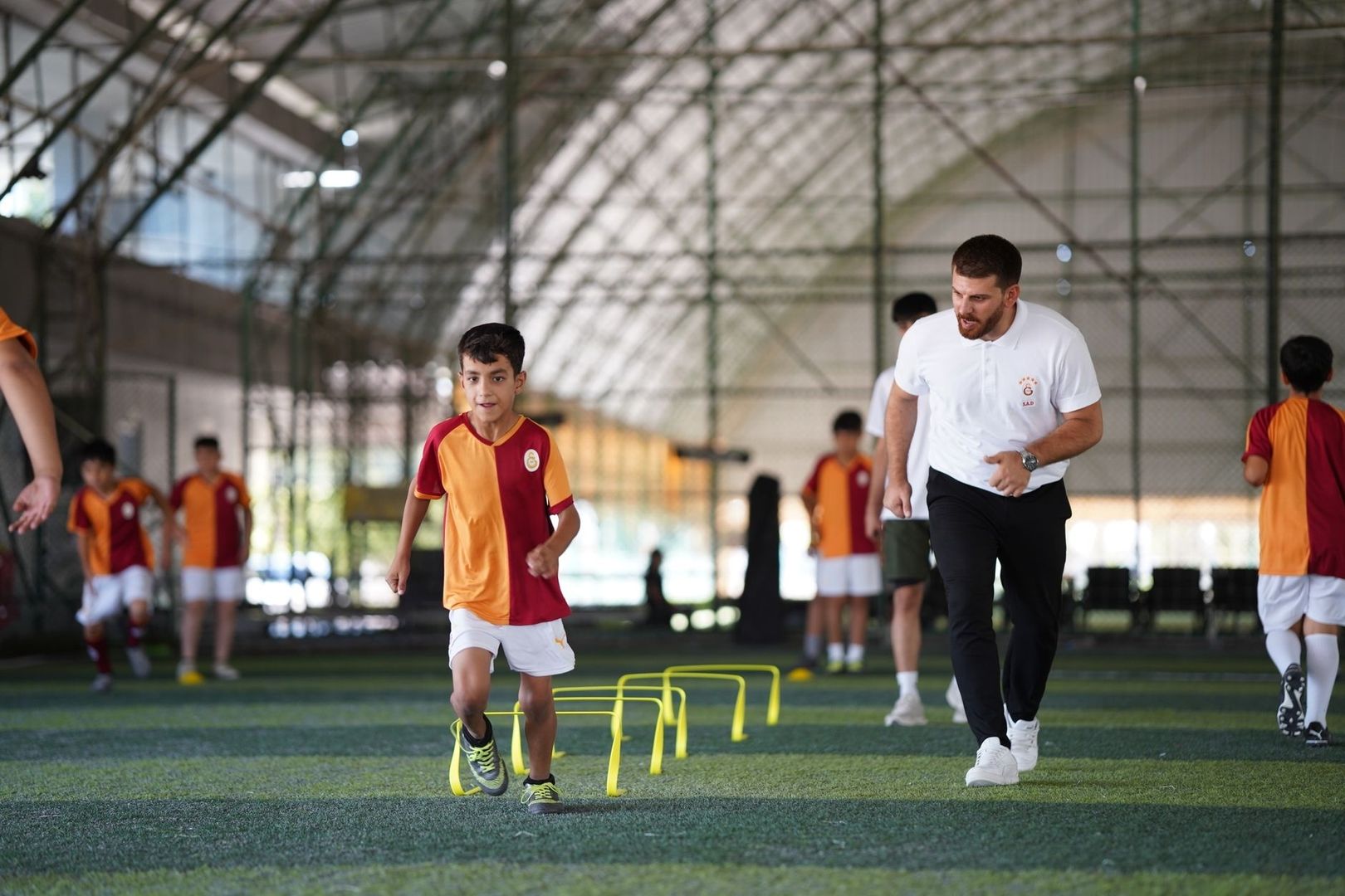 Young soccer players practice agility drills with a coach indoors