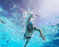 Swimmer moving underwater while wearing goggles and creating bubbles