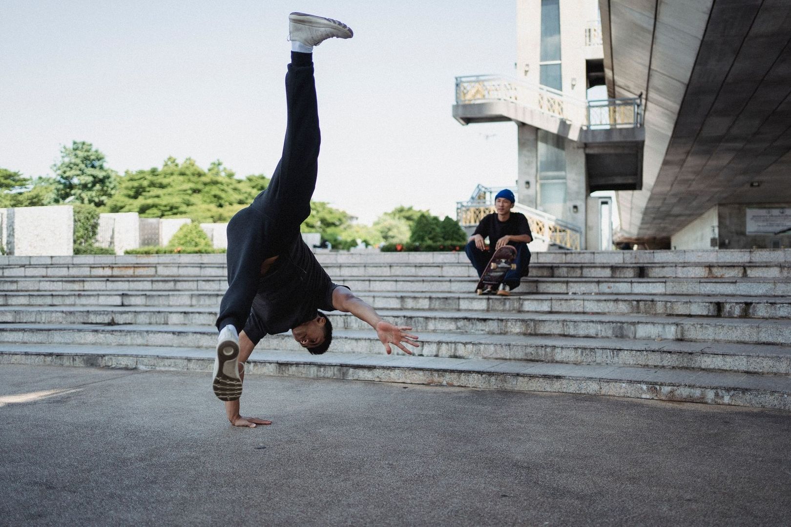 Athlete balances on one hand during a parkour move on concrete