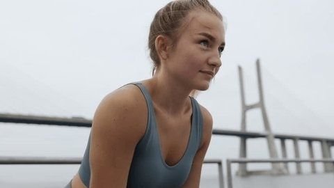 Focused female runner exercising near a bridge, appearing to control her breathing